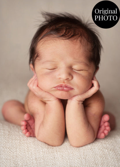 Newborn baby with hands under head on a neutral background