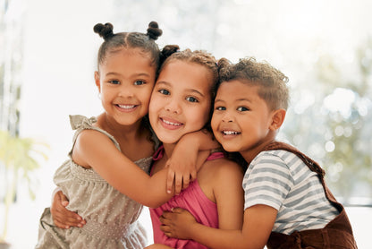 Three children hugging each other with a blurred background